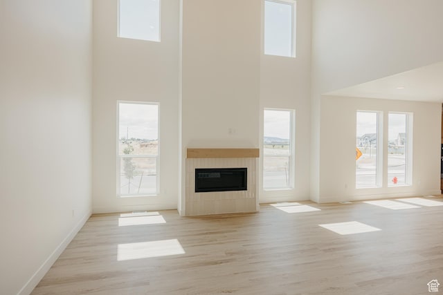 1026 W Chokecherry Dr Unit 135, Mapleton, UT 84664 - unfurnished living room with a towering ceiling, a tiled fireplace, and light wood-style floors