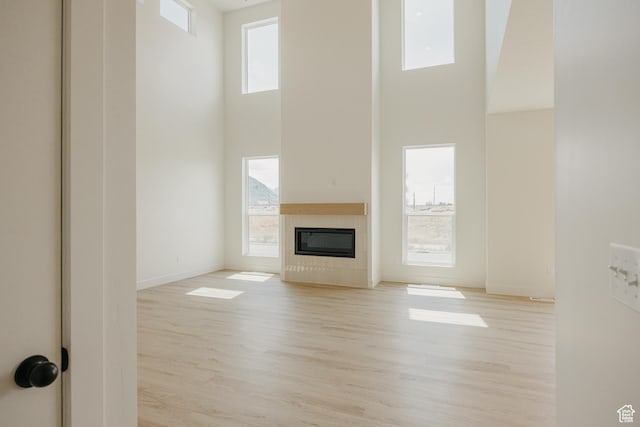1026 W Chokecherry Dr Unit 135, Mapleton, UT 84664 - unfurnished living room featuring a towering ceiling, a fireplace, and light wood-style floors