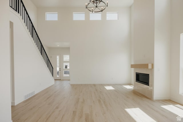 1026 W Chokecherry Dr Unit 135, Mapleton, UT 84664 - unfurnished living room featuring a high ceiling, a chandelier, light wood-style flooring, a glass covered fireplace, and stairway