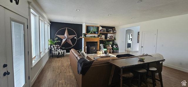 1275 S Lawrence Rd, Huntington, UT 84528 - living area with a textured ceiling, dark wood-style floors, a fireplace with raised hearth, arched walkways, and recessed lighting