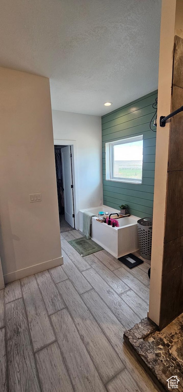 1275 S Lawrence Rd, Huntington, UT 84528 - bathroom featuring wood finished floors, a textured ceiling, and a garden tub