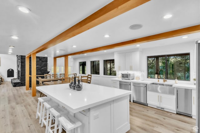 1960 N Lake Dr, Scofield, UT 84526 - kitchen with stainless steel dishwasher, white cabinetry, light countertops, a kitchen bar, and light wood-style flooring