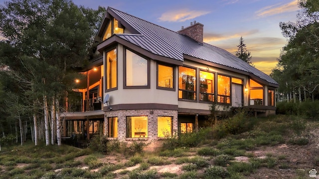 1960 N Lake Dr, Scofield, UT 84526 - back of house at dusk featuring a standing seam roof, a chimney, a balcony, a metal roof, and stucco siding