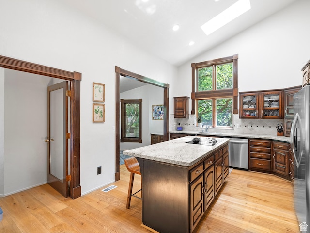 2586 S 1825 E, Ogden, UT 84401 - kitchen featuring appliances with stainless steel finishes, high vaulted ceiling, a skylight, light wood finished floors, and a center island