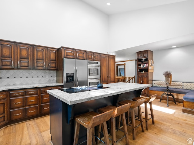 2586 S 1825 E, Ogden, UT 84401 - kitchen featuring appliances with stainless steel finishes, a towering ceiling, a center island, backsplash, and a breakfast bar area