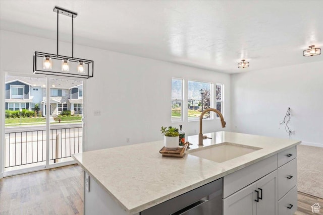 635 E Mayor Place Dr, American Fork, UT 84003 - kitchen with stainless steel dishwasher, light wood-type flooring, light stone counters, decorative light fixtures, and a center island with sink