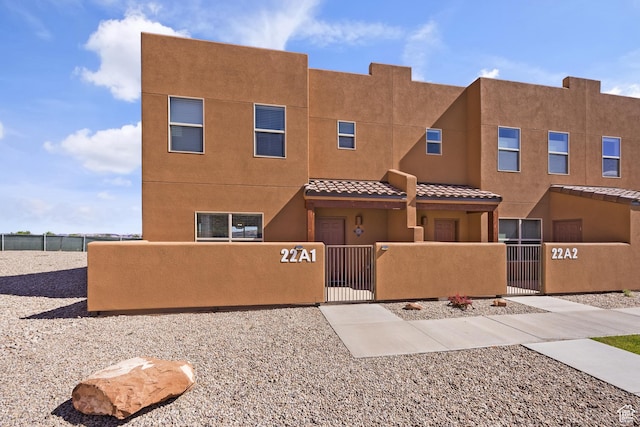 3853 Red Valley Cir Unit 22A1, Moab, UT 84532 - view of front of home featuring a fenced front yard, a gate, stucco siding, and a tile roof