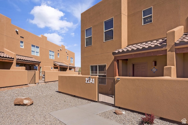 3853 Red Valley Cir Unit 22A1, Moab, UT 84532 - view of front of home with a gate, a fenced front yard, stucco siding, and a tiled roof