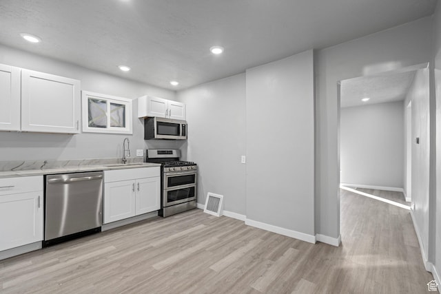 3174 S 9100 W, Magna, UT 84044 - kitchen with appliances with stainless steel finishes, light wood finished floors, white cabinets, recessed lighting, and light stone countertops