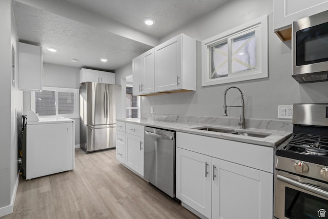 3174 S 9100 W, Magna, UT 84044 - kitchen with stainless steel appliances, washer and clothes dryer, a textured ceiling, white cabinets, and light wood-style floors