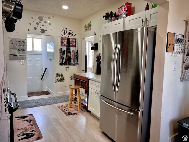 22 W 200 S, Tooele, UT 84074 - kitchen featuring freestanding refrigerator, white cabinets, light wood-style flooring, light countertops, and a textured ceiling
