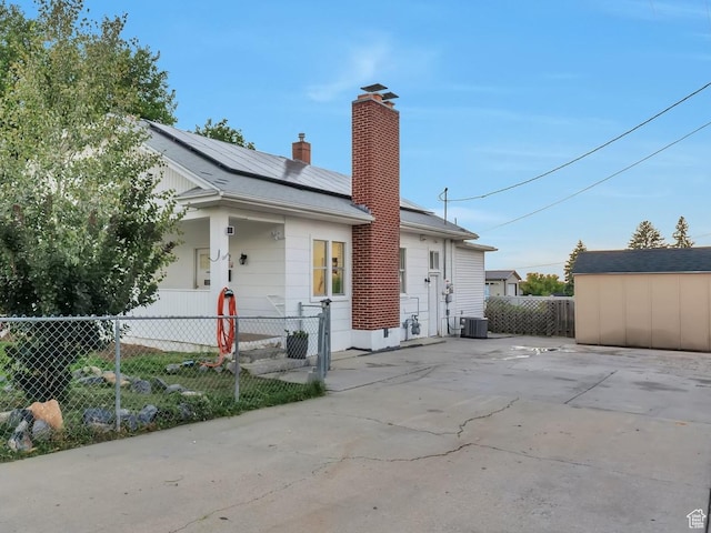 22 W 200 S, Tooele, UT 84074 - view of front facade featuring a chimney, roof mounted solar panels, and a shed