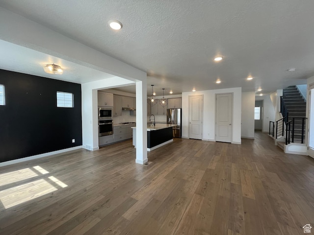 11766 S Watercourse Rd, South Jordan, UT 84009 - unfurnished living room with stairs, wood finished floors, recessed lighting, and a textured ceiling