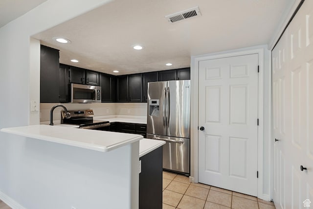 3760 S Carlisle Park Pl W Unit 3, Salt Lake City, UT 84119 - kitchen featuring appliances with stainless steel finishes, dark cabinets, light tile patterned floors, a peninsula, and light countertops