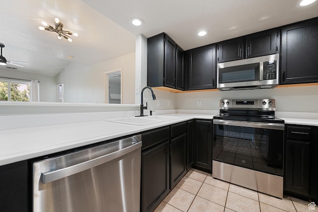 3760 S Carlisle Park Pl W Unit 3, Salt Lake City, UT 84119 - kitchen featuring appliances with stainless steel finishes, dark cabinetry, light tile patterned floors, light countertops, and recessed lighting