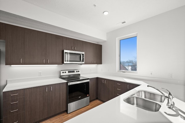 1034 W 1700 S Unit 124, Salt Lake City, UT 84104 - kitchen featuring stainless steel appliances, light wood finished floors, light countertops, dark brown cabinetry, and recessed lighting