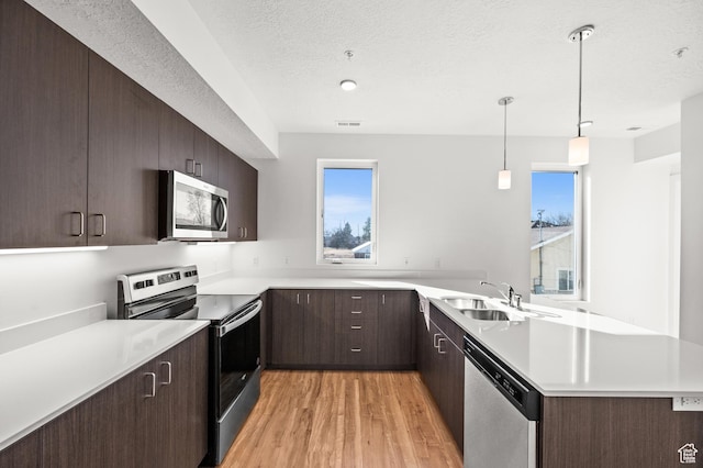 1034 W 1700 S Unit 124, Salt Lake City, UT 84104 - kitchen with stainless steel appliances, light countertops, light wood finished floors, dark brown cabinetry, and a textured ceiling