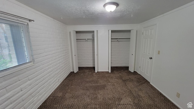 4531 S 700th St E, Murray, UT 84107 - unfurnished bedroom with multiple closets, dark colored carpet, a textured ceiling, and brick wall