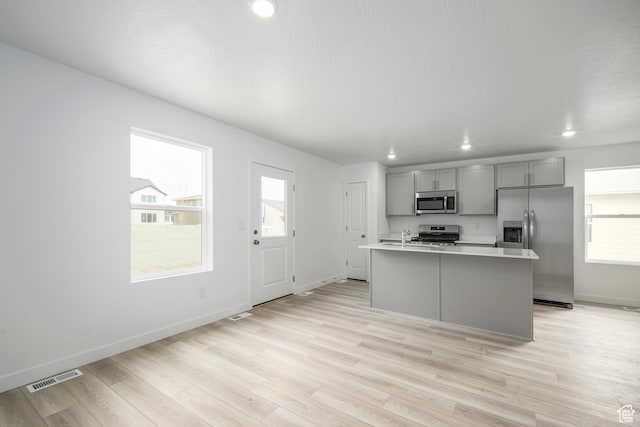 1857 E Bison Dr Unit B217, Eagle Mountain, UT 84005 - kitchen featuring appliances with stainless steel finishes, gray cabinets, light countertops, light wood-style flooring, and a kitchen island with sink