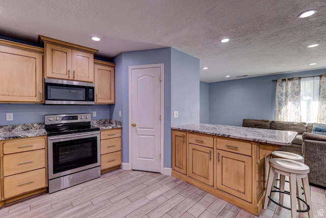 709 N 2200 E, St George, UT 84790 - kitchen with stainless steel appliances, open floor plan, light wood finished floors, light brown cabinetry, and recessed lighting