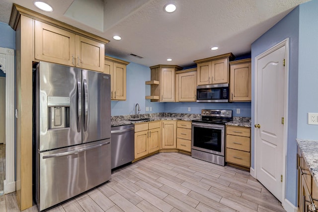 709 N 2200 E, St George, UT 84790 - kitchen featuring appliances with stainless steel finishes, light brown cabinets, wood finish floors, light stone counters, and a textured ceiling