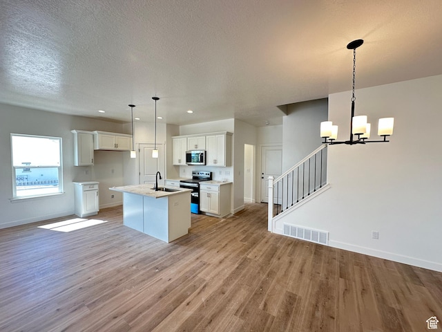 306 E 1480 N Unit 44, Salem, UT 84653 - kitchen featuring stainless steel appliances, light wood finished floors, an island with sink, open floor plan, and a chandelier