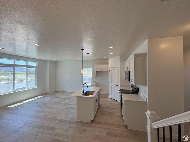 306 E 1480 N Unit 44, Salem, UT 84653 - kitchen featuring electric range oven, stainless steel microwave, light wood-style floors, a center island with sink, and a textured ceiling