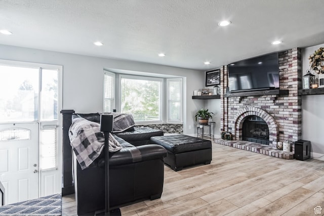 254 W 1600 N, Harrisville, UT 84404 - living area featuring wood finished floors, a brick fireplace, a textured ceiling, and recessed lighting