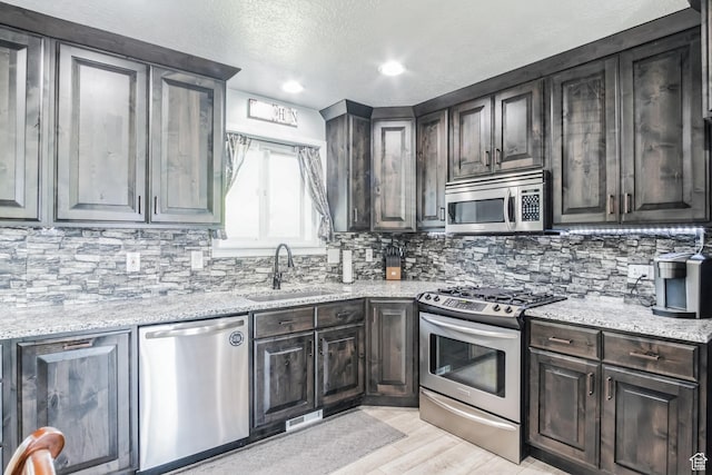 254 W 1600 N, Harrisville, UT 84404 - kitchen featuring stainless steel appliances, backsplash, light wood-style floors, light stone countertops, and a textured ceiling
