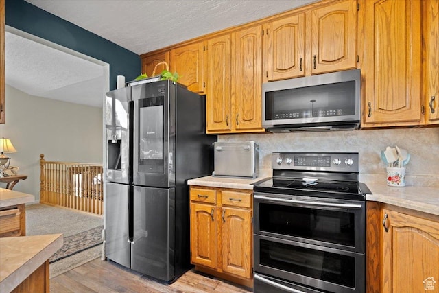 7351 W Zana Ln, Magna, UT 84044 - kitchen with stainless steel appliances, light countertops, light wood-style floors, decorative backsplash, and a textured ceiling