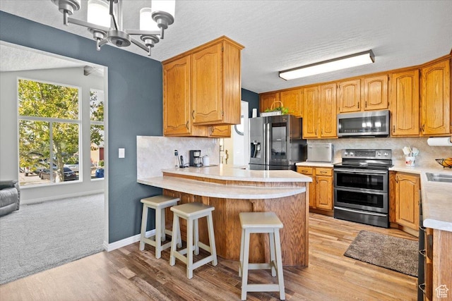 7351 W Zana Ln, Magna, UT 84044 - kitchen featuring appliances with stainless steel finishes, a peninsula, light countertops, decorative backsplash, and a textured ceiling