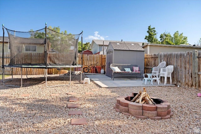 7351 W Zana Ln, Magna, UT 84044 - fenced backyard with a trampoline, a storage unit, an outdoor fire pit, and a patio area