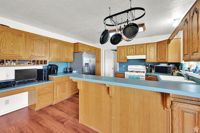 5548 W 4350 S, Hooper, UT 84315 - kitchen with appliances with stainless steel finishes, under cabinet range hood, a textured ceiling, light wood-type flooring, and a peninsula