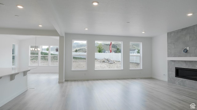 903 W Fallow Dr Unit 212, Saratoga Springs, UT 84045 - unfurnished living room with healthy amount of natural light, a tile fireplace, wood finished floors, a chandelier, and recessed lighting