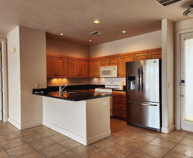 225 N Country Ln Unit 5, St George, UT 84770 - kitchen featuring white appliances, dark countertops, a peninsula, brown cabinets, and recessed lighting