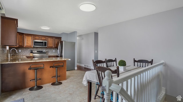 285 W 90 N, Clearfield, UT 84015 - kitchen featuring stainless steel appliances, decorative backsplash, light stone counters, a peninsula, and a kitchen bar