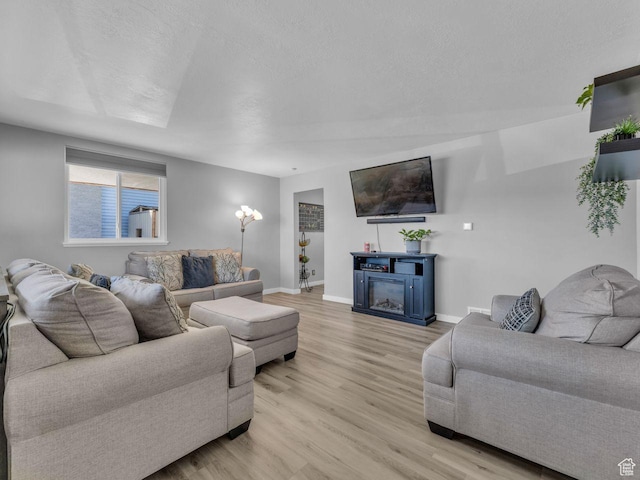 4273 W Annapolis Dr S, West Valley City, UT 84120 - living room featuring light wood finished floors, a glass covered fireplace, and a textured ceiling