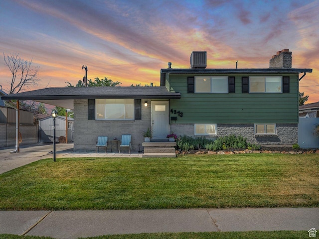 4273 W Annapolis Dr S, West Valley City, UT 84120 - split level home with a lawn, a chimney, an attached carport, and a storage unit