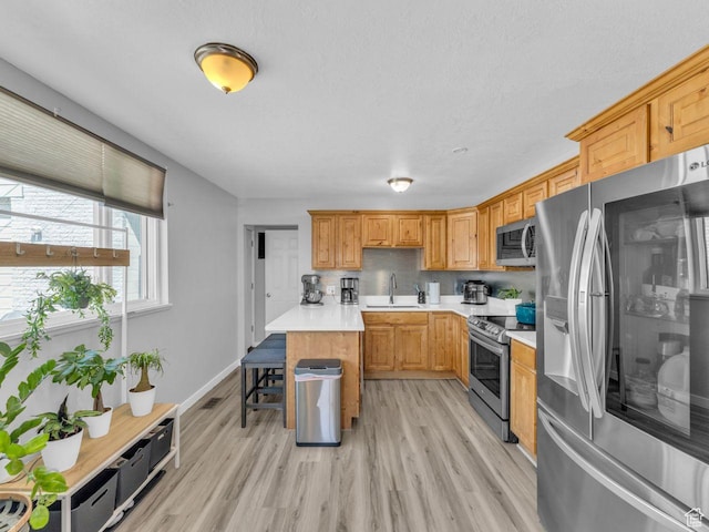 4273 W Annapolis Dr S, West Valley City, UT 84120 - kitchen with stainless steel appliances, light countertops, light wood-style floors, decorative backsplash, and a breakfast bar