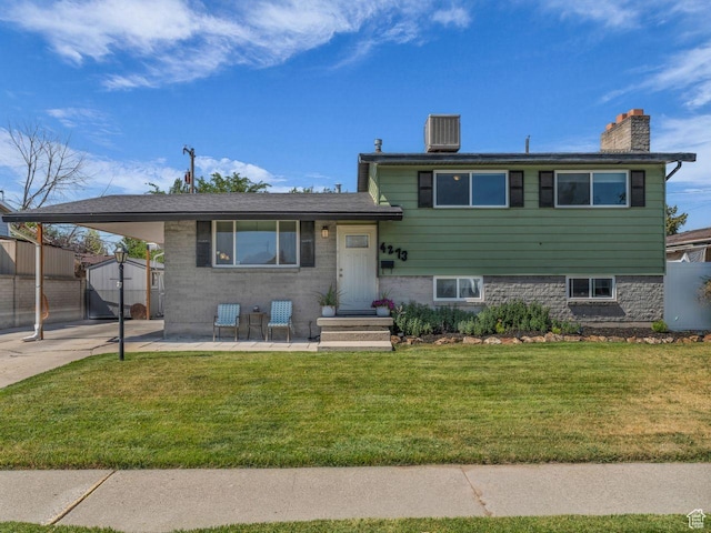 4273 W Annapolis Dr S, West Valley City, UT 84120 - tri-level home featuring a chimney, a carport, a front yard, a storage unit, and concrete driveway