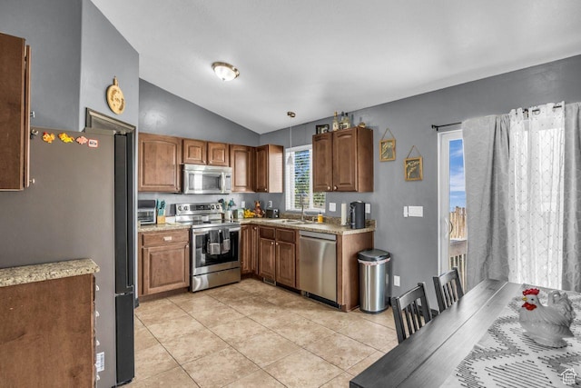 726 S 1050 W, Tooele, UT 84074 - kitchen with stainless steel appliances, vaulted ceiling, light tile patterned flooring, light countertops, and brown cabinets