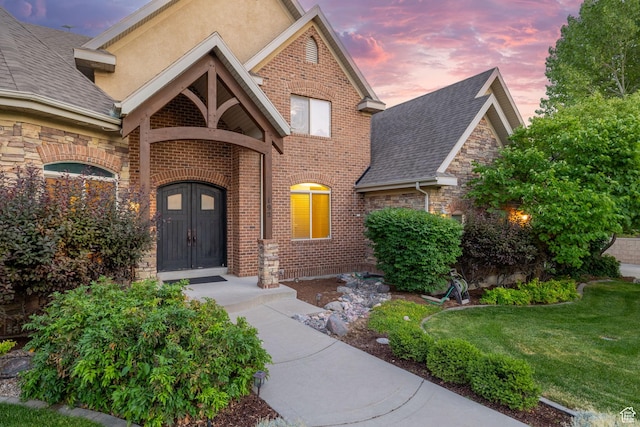 192 E 2200 N, Lehi, UT 84043 - exterior entry at dusk with a lawn, brick siding, stone siding, and roof with shingles