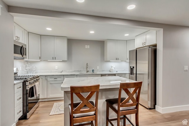 467 E Island View Cir N, Farmington, UT 84025 - kitchen with appliances with stainless steel finishes, light wood-style flooring, light stone countertops, a kitchen bar, and a center island