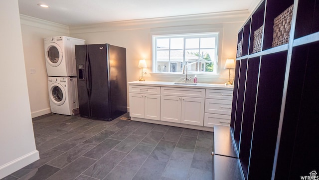 2295 E Woodchuck Way, Sandy, UT 84093 - kitchen with stacked washer and clothes dryer, black fridge with ice dispenser, ornamental molding, white cabinets, and light countertops