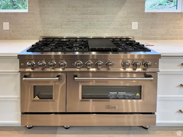 10135 E Clubhouse Rd, Heber City, UT 84032 - kitchen view of range with two ovens, decorative backsplash, white cabinetry, light stone counters, and wood finished floors