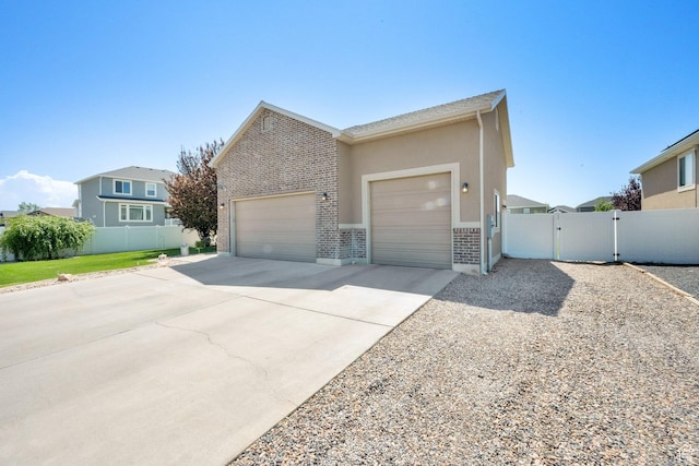 5295 S 4425 W, Hooper, UT 84315 - view of front of house featuring an attached garage, concrete driveway, brick siding, and a gate