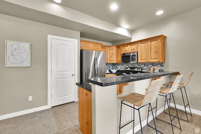 1028 W 950 N, Layton, UT 84041 - kitchen with appliances with stainless steel finishes, tasteful backsplash, a breakfast bar area, a peninsula, and tile countertops