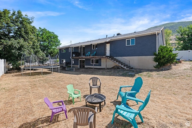 1851 N Main St, Centerville, UT 84014 - rear view of house featuring a fire pit, a trampoline, stairs, a fenced backyard, and brick siding