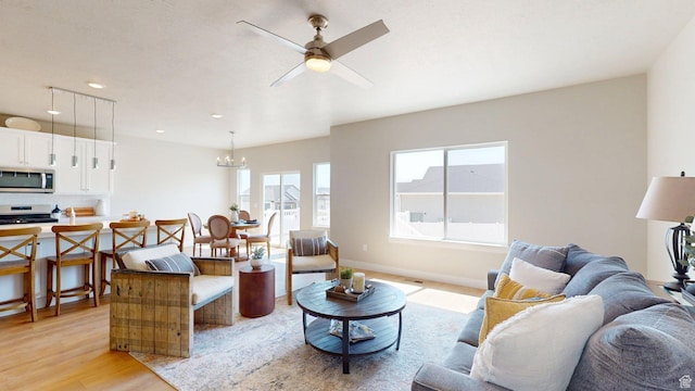 7497 W Sage Slope Way, Herriman, UT 84096 - living room featuring light wood-type flooring, healthy amount of natural light, a ceiling fan, a chandelier, and recessed lighting