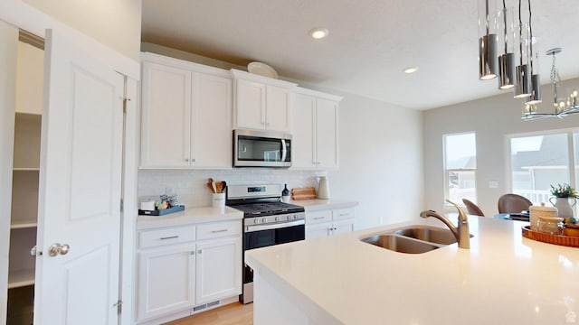 7497 W Sage Slope Way, Herriman, UT 84096 - kitchen with appliances with stainless steel finishes, backsplash, light countertops, white cabinets, and pendant lighting
